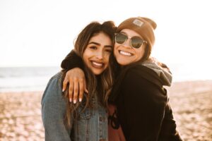 A pair of friends smiling on the beach.