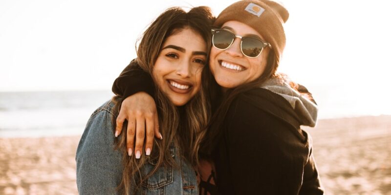 A pair of friends smiling on the beach.