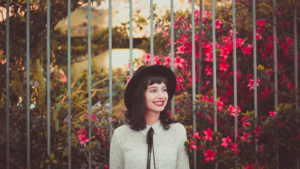 A young woman smiling happily amongst flowers.